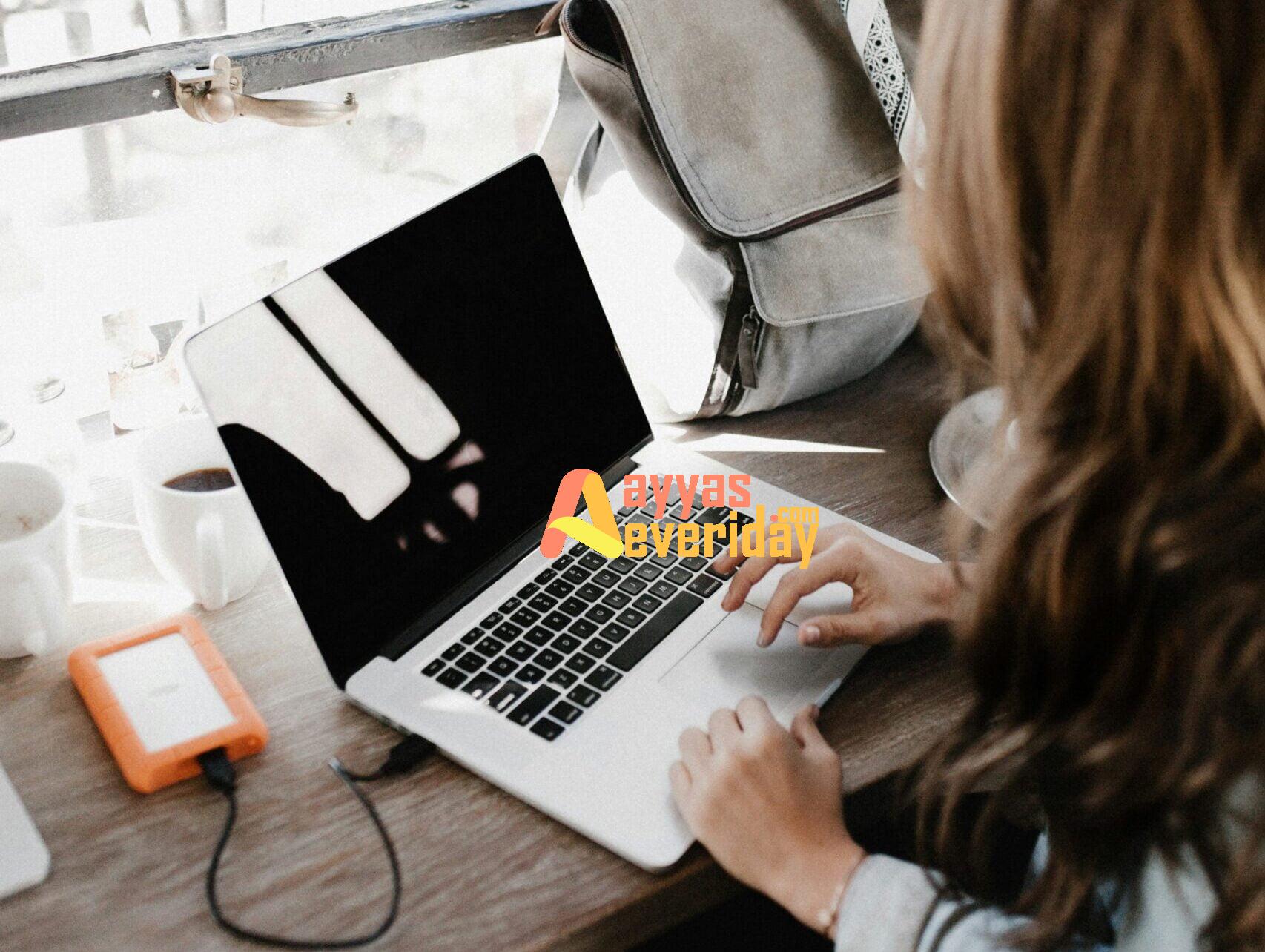 girl wearing grey long-sleeved shirt using MacBook Pro on brown wooden table