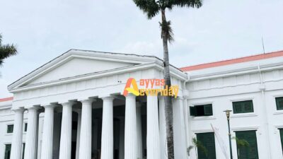 a large white building with columns and palm trees